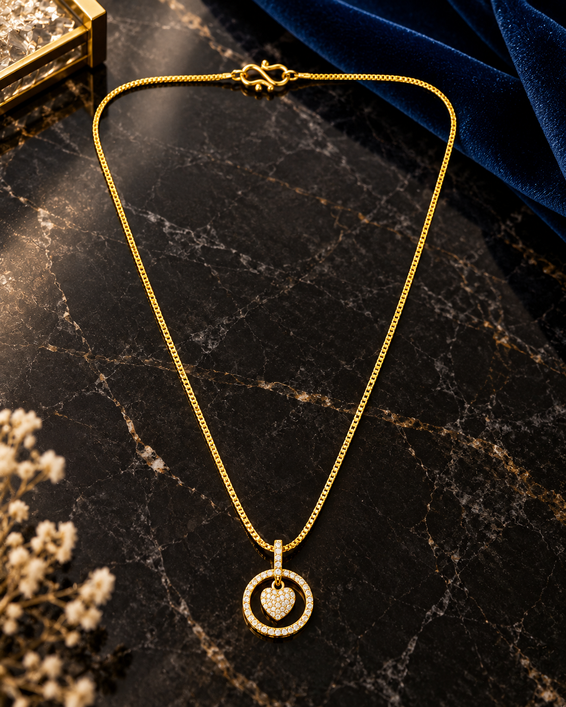 A gold chain necklace with a heart-shaped pendant set in a circular ring design.
